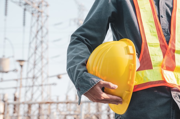 Le casque de sécurité jaune est entre les mains d'un électricien.