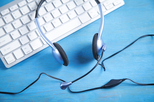 Casque de service client et clavier d'ordinateur sur fond bleu.