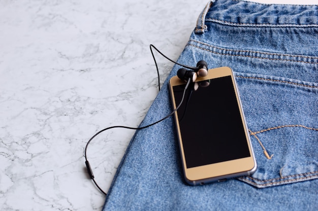 Casque et smartphone dans la poche d&#39;un jean, gros plan