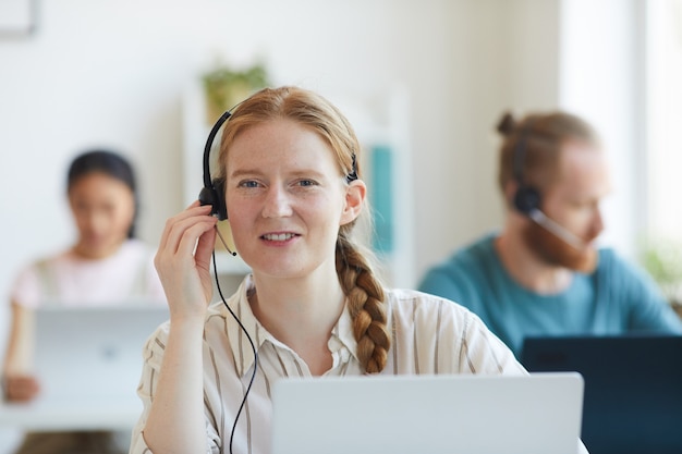 Casque de télémarketing femme du centre d'appels femme dans les écouteurs parlant avec le client pendant son travail au bureau