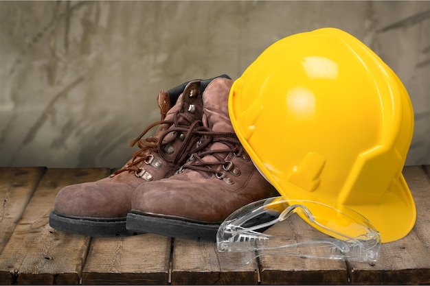 Casque de travail jaune et bottes de travail sur fond de mur