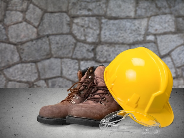 Casque de travail jaune et bottes de travail sur fond de mur