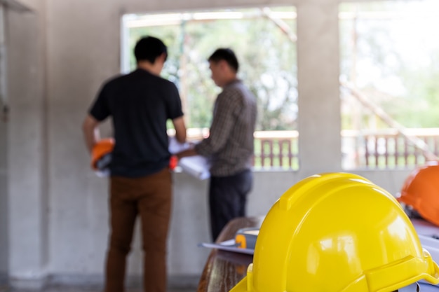 Casques sur le bureau devant l&#39;ingénieur ou l&#39;architecte discutant avec le contremaître