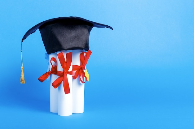 Casquette de graduation sur les diplômes sur fond bleu