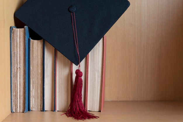 Casquette graduée noire et pompon rouge posé sur le livre.