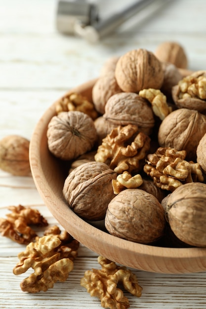 Casse-noisette et bol de noix sur fond de bois blanc