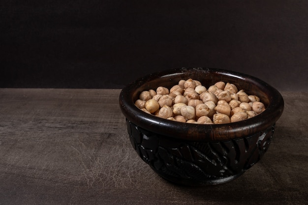 Casserole en bois foncé avec des pois chiches non cuits sur une planche de bois