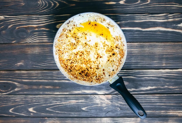 Casserole brûlée dans l'huile Ustensiles de cuisine endommagés Fond de bois Nourriture malsaine