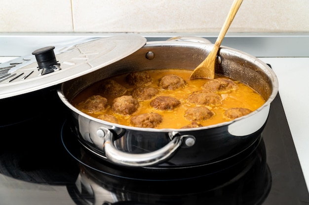 Casserole avec de délicieuses boulettes de viande dans la sauce mijotant sur la cuisinière