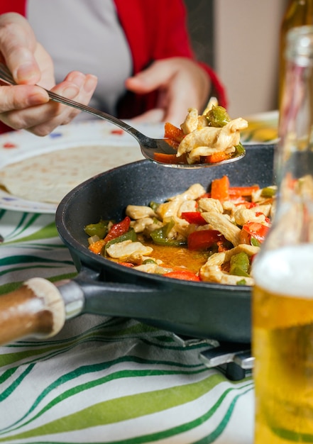 Casserole avec des fajitas mexicaines sur une table avec une personne servant de la nourriture