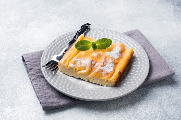 Casserole de fromage cottage sur une assiette avec du sucre en poudre et des feuilles de menthe.