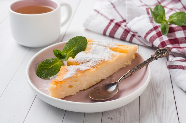 Casserole de fromage cottage sur une assiette avec du sucre en poudre et des feuilles de menthe.