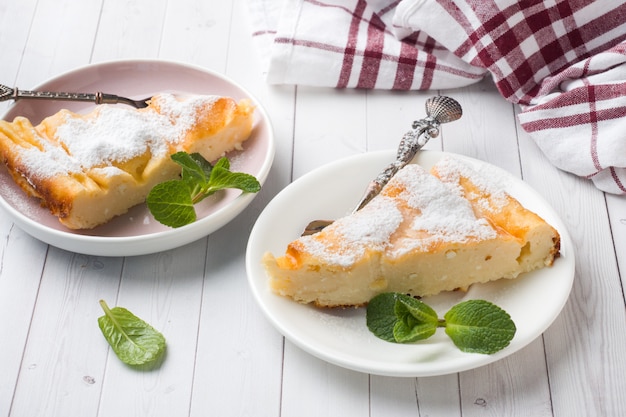 Casserole de fromage cottage sur une assiette avec du sucre en poudre et des feuilles de menthe.