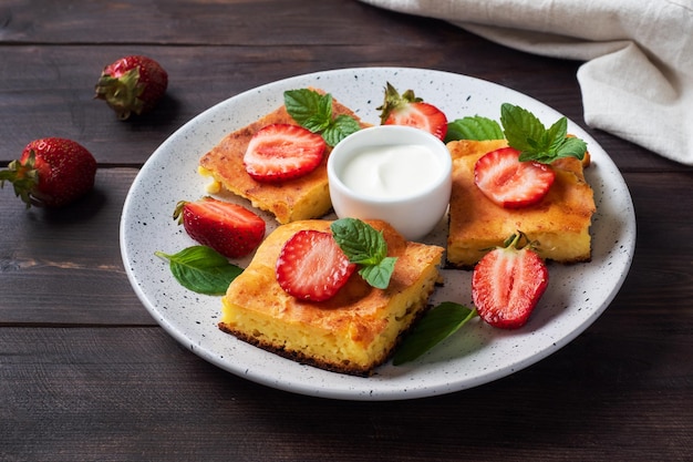 Casserole de fromage cottage aux fraises et à la menthe Délicieux dessert fait maison à base de lait caillé et de baies fraîches avec espace de copie de fond en bois foncé crème