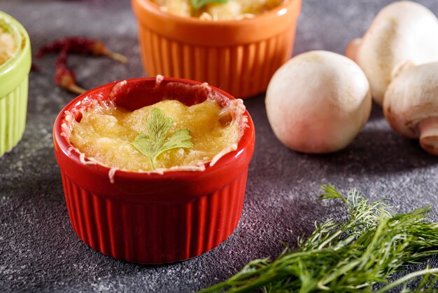 Casserole Gros plan avec du poulet et des champignons sous la croûte de fromage dans des noix de coco multicolores sur fond gris