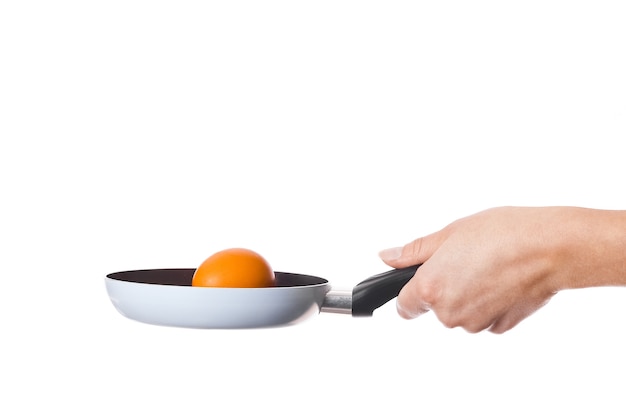 Une casserole en mains sur un mur blanc