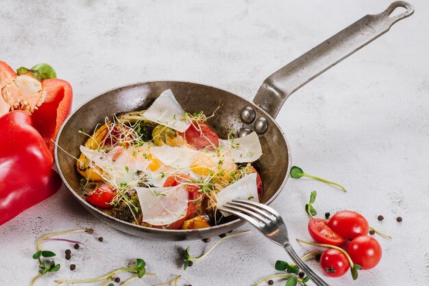 Une casserole avec des œufs au plat avec du parmesan et des légumes