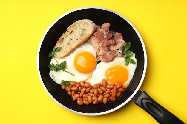 Casserole avec petit déjeuner savoureux sur fond jaune