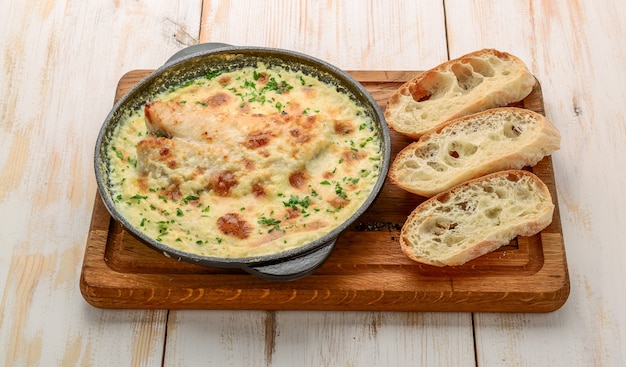 Casserole de poisson blanc avec du fromage, de la crème sure et de l'oignon sur une table en bois