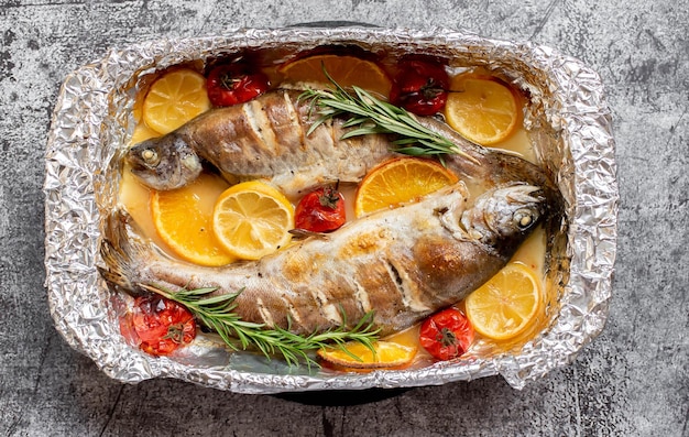 Une casserole de poisson avec des légumes et des herbes dessus