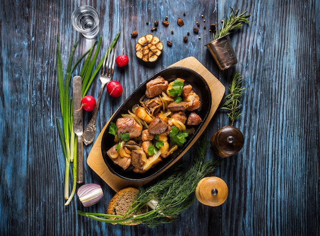 Casserole de porc rôti en tranches et légumes sur fond en bois rustique