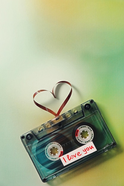 Photo cassette audio rétro avec bande en forme de coeur sur fond flou vert