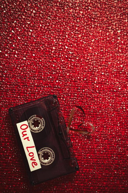 Cassette audio rétro avec ruban en forme de coeur sur fond texturé rouge