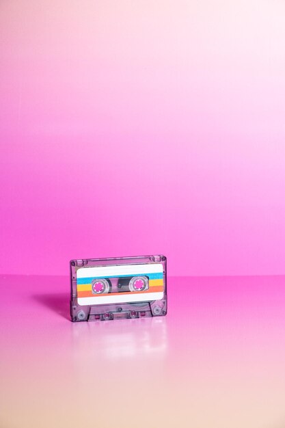Une cassette audio transparente avec des étiquettes sur fond fuchsia