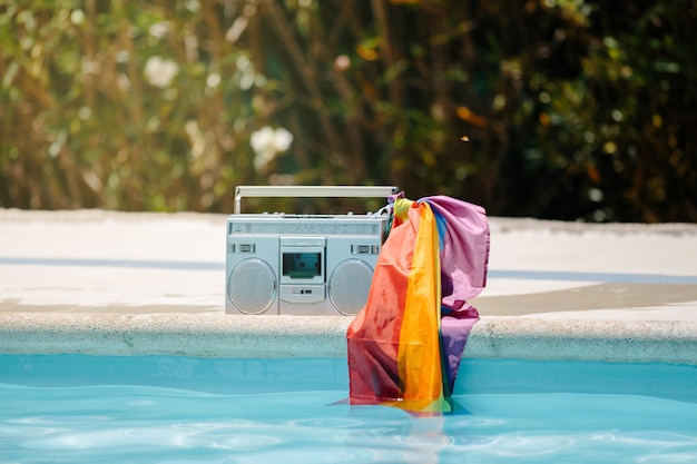 Cassette radio en métal avec un drapeau lgtb attaché à la poignée d'une piscine