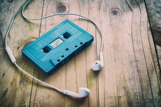 Cassette rétro bleu et écouteur blanc sur la table en bois