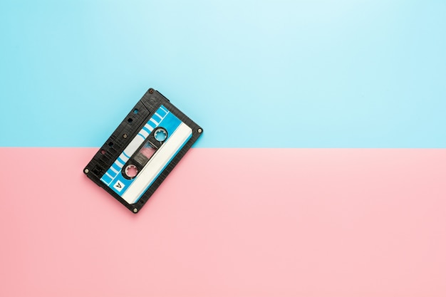 Cassette à ruban noir sur fond bleu et rose.