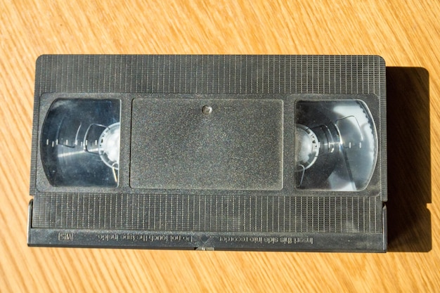 Une cassette vidéo vintage sur une table en bois sur fond beige