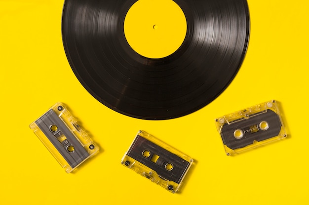 Cassettes transparentes et disque vinyle sur fond jaune