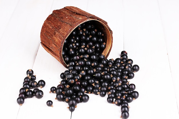 Cassis dans une tasse en bois sur fond de bois