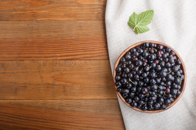 Cassis frais dans un bol en bois sur fond en bois. vue de dessus.