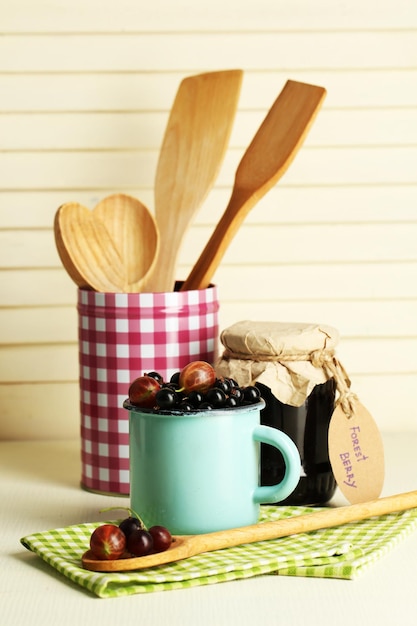 Cassis mûrs dans une tasse et un bocal en verre avec de la confiture savoureuse sur fond de bois clair