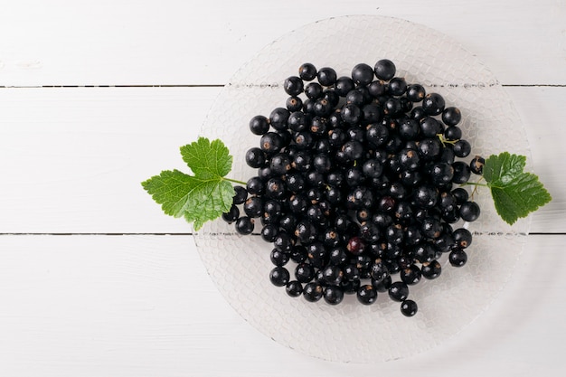 Cassis sur table en bois avec brin de feuille