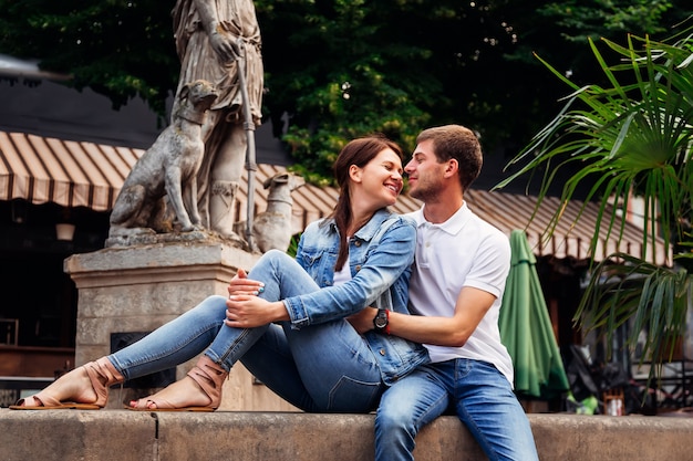 Casual couple mignon assis sur une fontaine