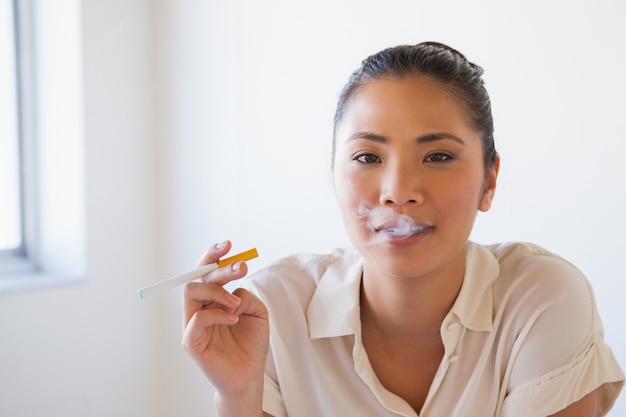 Casual femme d&#39;affaires, fumant une cigarette électronique