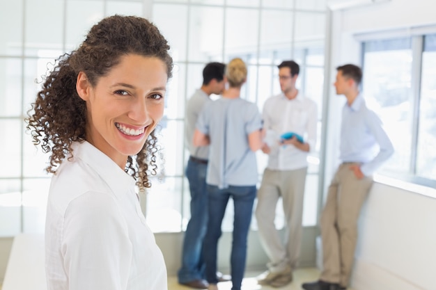 Casual femme d&#39;affaires, souriant à la caméra avec l&#39;équipe derrière elle