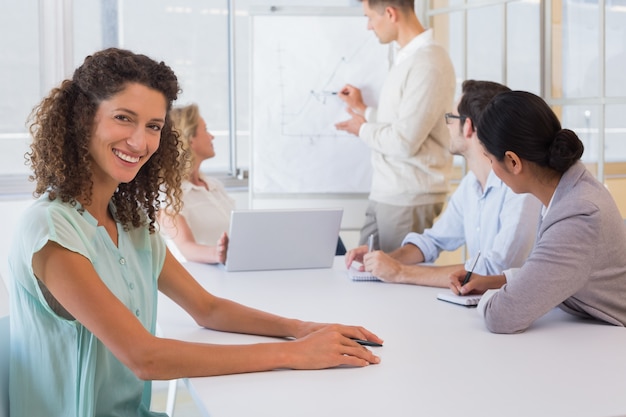 Casual femme d&#39;affaires, souriant à la caméra pendant la réunion