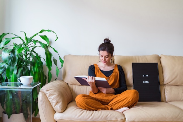 Casual femme assise sur le canapé dans sa maison. Restez à la maison. Virus pandémique Coronavirus Covid 19.