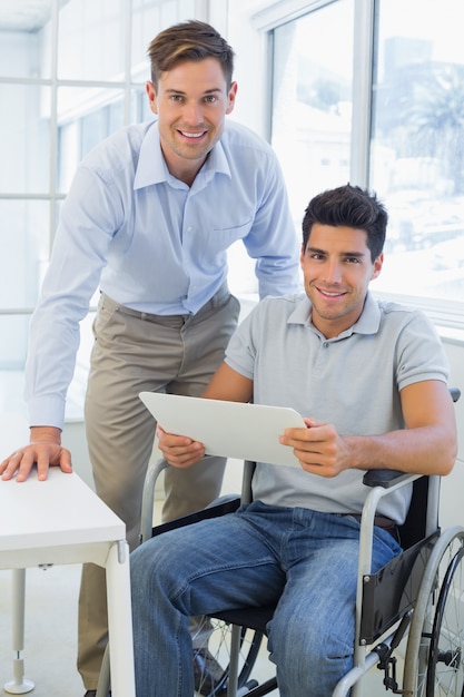 Casual homme d&#39;affaires en fauteuil roulant, souriant à la caméra avec un collègue