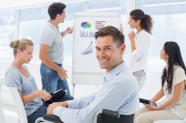 Casual homme d&#39;affaires en fauteuil roulant, souriant à la caméra lors de la présentation au bureau