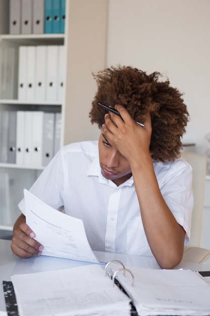 Casual homme d&#39;affaires stressé, en passant par la paperasserie à son bureau