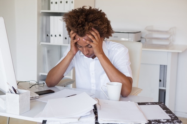 Casual homme d&#39;affaires stressé avec sa tête au bureau