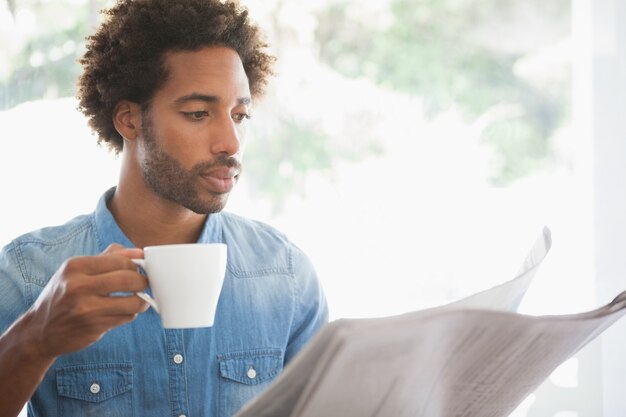 Casual homme prenant un café en lisant un journal