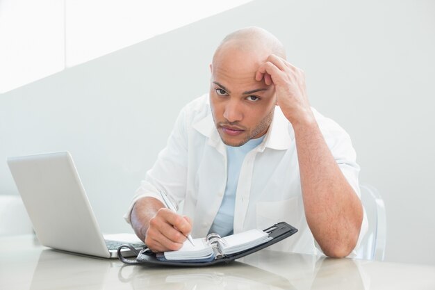 Casual homme sérieux avec ordinateur portable écrit dans le journal