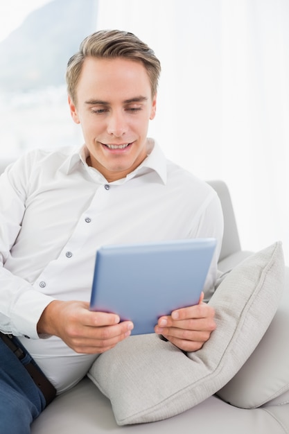 Casual jeune homme à l&#39;aide de tablette numérique sur le canapé