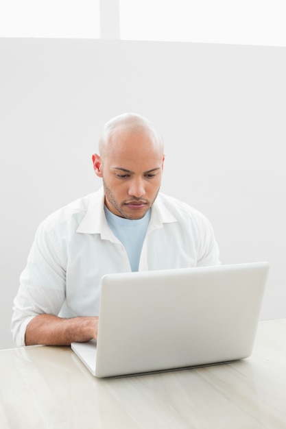 Casual jeune homme sérieux à l&#39;aide d&#39;ordinateur portable au bureau